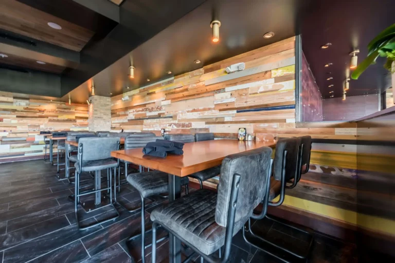 Close view of a high-top table with leather chairs against a reclaimed wood wall at Tap 42 Aventura