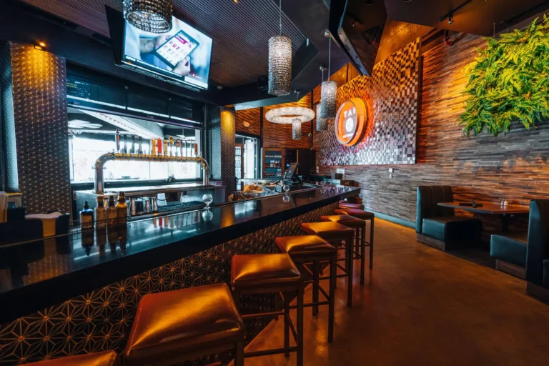 Indoor bar with geometric tile front, leather stools, beer taps and a glowing logo beside booth seating at Tap 42 Boca Raton