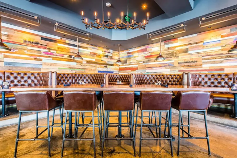 Communal high-top with leather bar chairs, candle chandelier and colorful reclaimed wood walls at Tap 42 Coral Gables