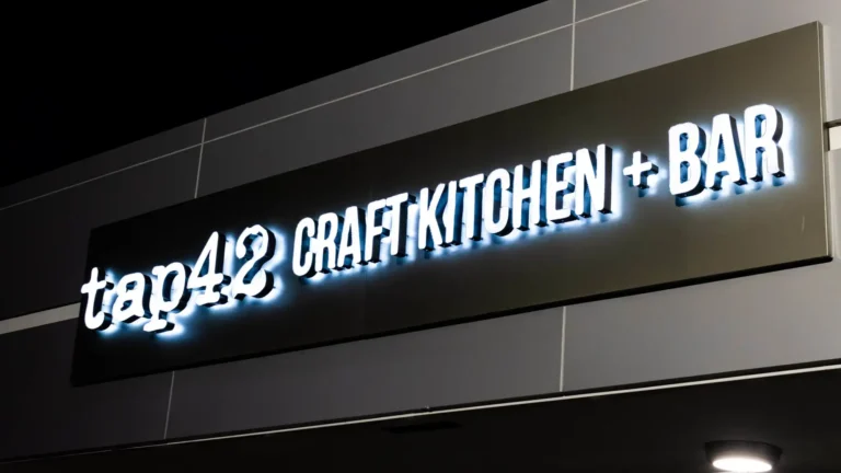 Illuminated Craft Kitchen + Bar sign on the building facade at night at Tap 42 Coral Springs