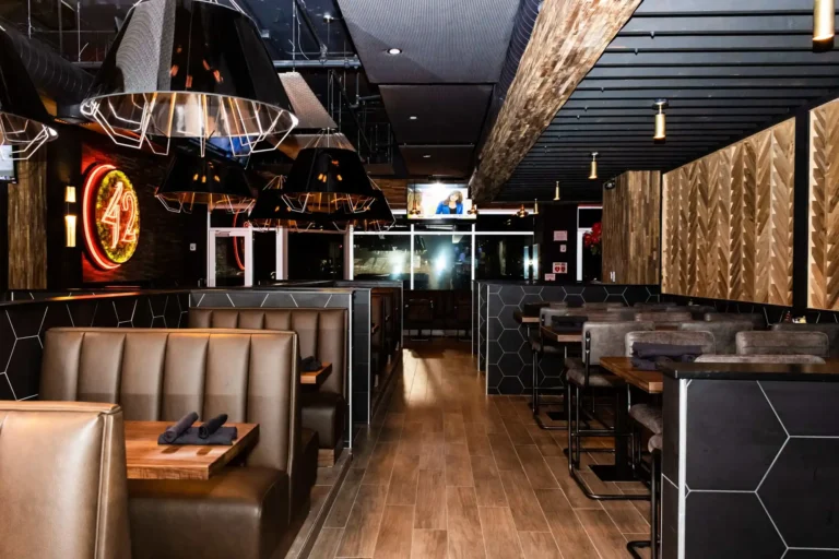 Aisle between leather booths and high-tops with chevron wood wall panels at Tap 42 Coral Springs