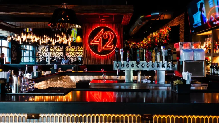 Neon 42 sign reflected on the bar top behind a row of craft beer taps at Tap 42 Doral