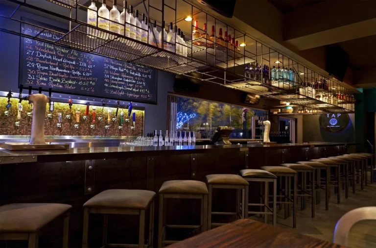 Bar stools facing beer taps, chalkboard beer list and lit liquor shelves at Tap 42 Fort Lauderdale