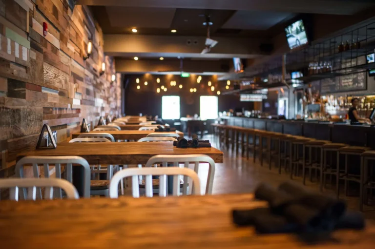 Communal tables beside a reclaimed wood wall with the long bar in soft focus at Tap 42 Fort Lauderdale