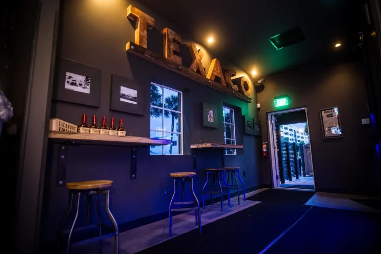 Vintage Texaco letters above a drink rail with stools and framed photos at Tap 42 Fort Lauderdale