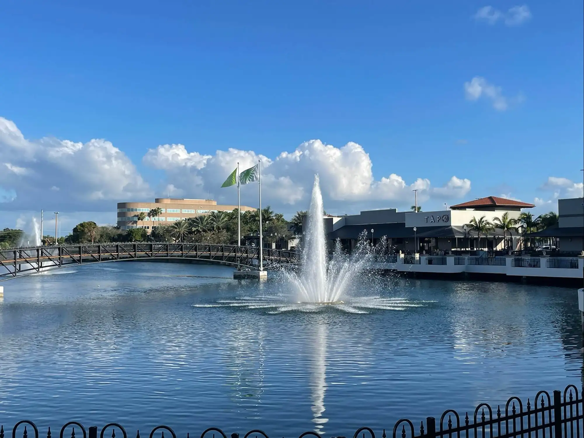 Lake with a fountain and footbridge facing the waterfront restaurant building at Tap 42 Kendall