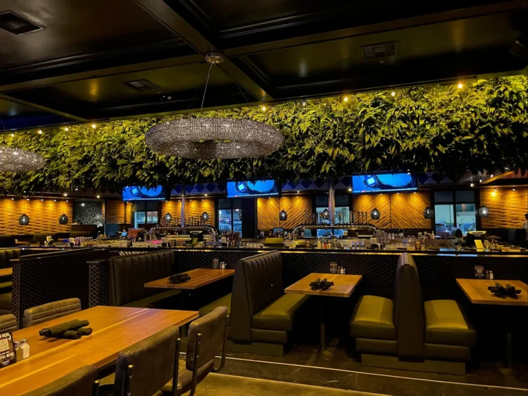 Booths and dining tables beneath a hanging green wall and crystal chandelier at Tap 42 Kendall