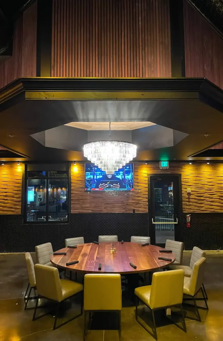 Round wood table with yellow leather chairs under a crystal chandelier in private dining at Tap 42 Kendall