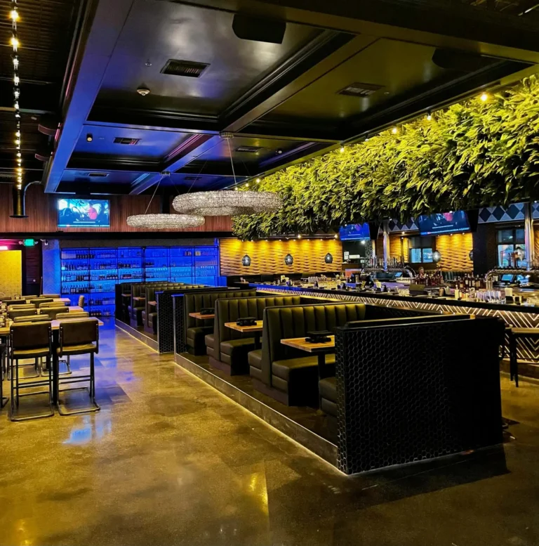 Leather booths and high-tops with ring chandeliers and a blue-lit wine wall at Tap 42 Kendall