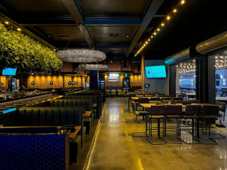 Dining room with booths, high-top tables and ring chandeliers beside the open patio at Tap 42 Kendall