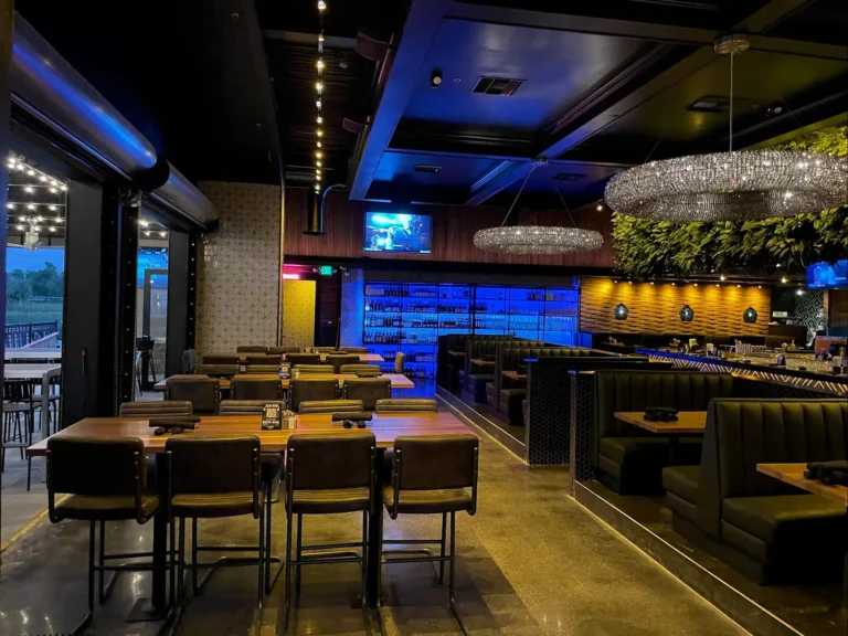 High-top tables near the open patio wall with booths and a blue-lit wine display at Tap 42 Kendall