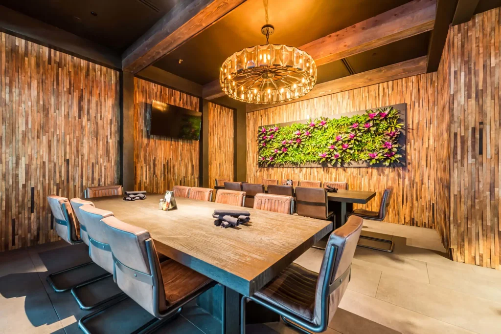Private dining room with long wood table, glass chandelier and living plant wall at Tap 42 Midtown Miami