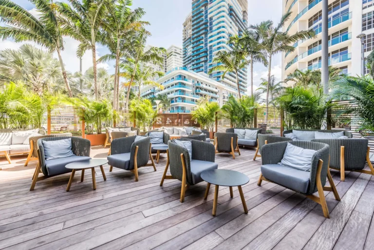 Open-air deck lounge with woven armchairs, palm trees and high-rise views at Tap 42 Midtown Miami
